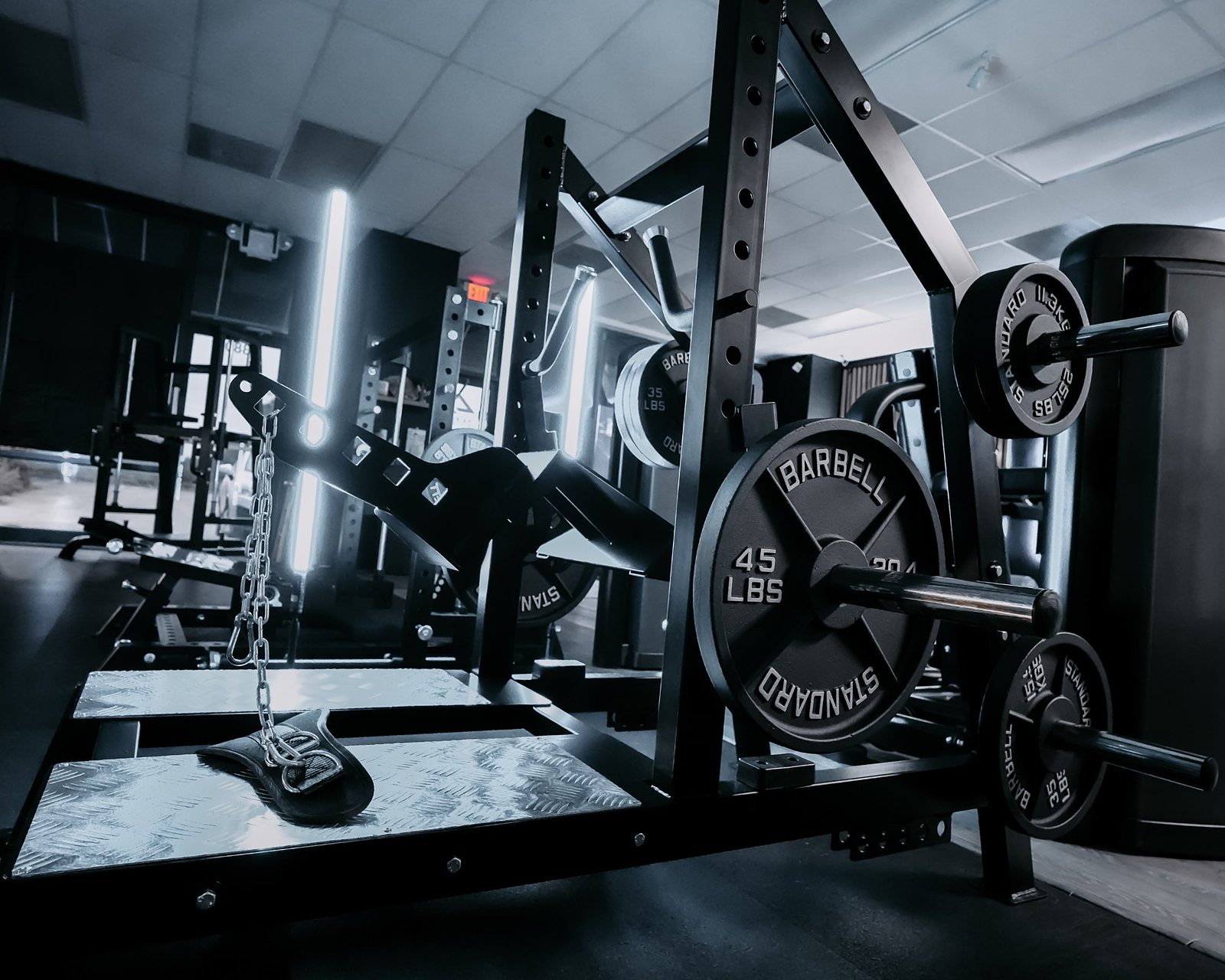 Plate-loaded belt squat on the floor at an Aira Fitness gym